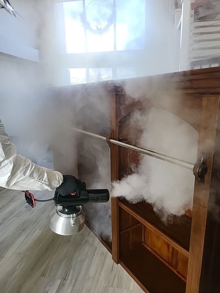 Technician thermal fogging wood cabinet interior for smoke odor penetration